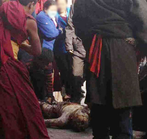 A women looks at the burned body of Dorje Rinchen