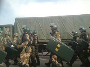 A squad of PAP march past a PAP truck in Rebkong.