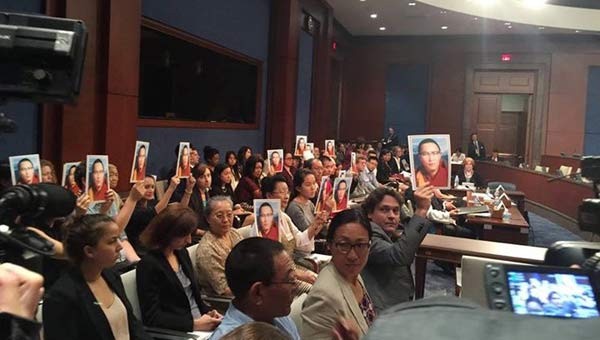 During a moment of silence for Tenzin Delek Rinpoche many people held his photo above their heads.